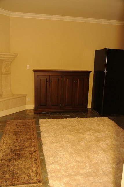 Living room with dark wood cabinet, tiled floor, and patchwork rug. - 4069 West 37th Ave, Vancouver West Side