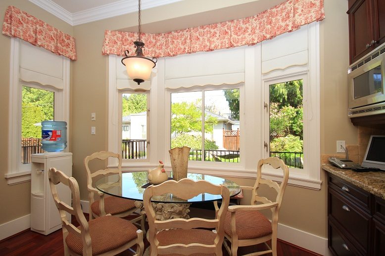 Bright dining nook with glass table, floral curtains, and hardwood floors. - 4069 West 37th Ave, Vancouver West Side