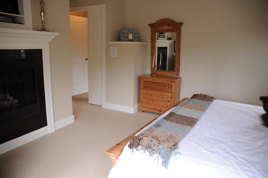 Furnished bedroom with wooden dresser, mirror, and fireplace. - 4069 West 37th Ave, Vancouver West Side