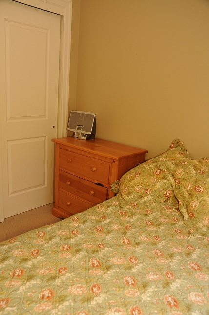 Bedroom with floral bedding and wooden nightstand. - 4069 West 37th Ave, Vancouver West Side