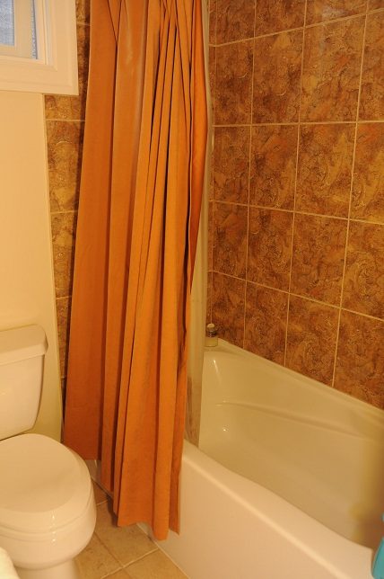 Bathroom with orange shower curtain and tiled walls. - 4069 West 37th Ave, Vancouver West Side