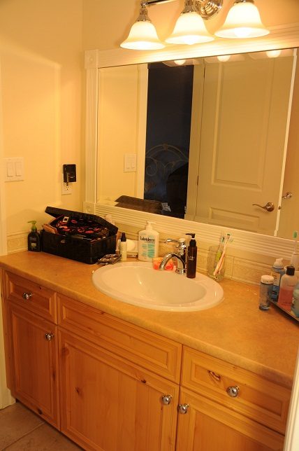 Bathroom with wooden cabinets, countertop, and mirror reflecting door. - 4069 West 37th Ave, Vancouver West Side