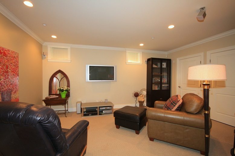 Living room with leather furniture, TV, and bookshelf. - 4069 West 37th Ave, Vancouver West Side