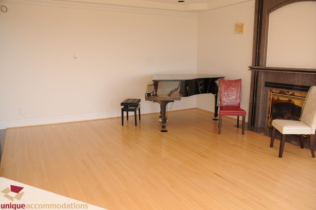 Living room with hardwood floors, piano, and fireplace. - 4139 Citadel Court, North Vancouver