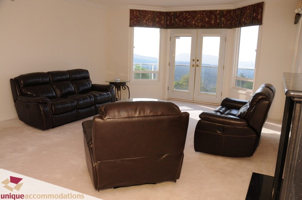 Bright living room with leather furniture and city view. - 4139 Citadel Court, North Vancouver
