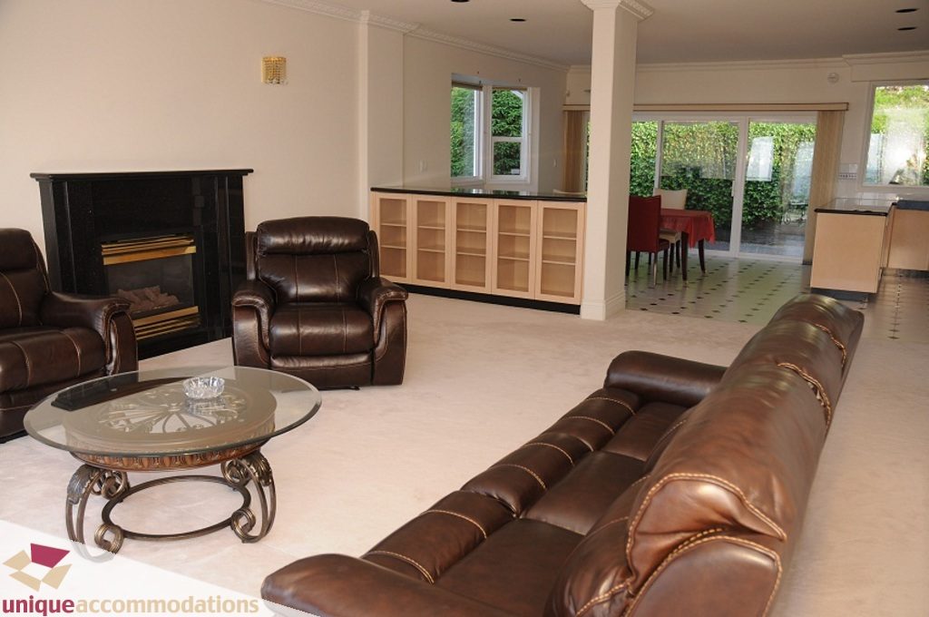 Spacious living room with leather furniture, glass coffee table, and large windows. - 4139 Citadel Court, North Vancouver