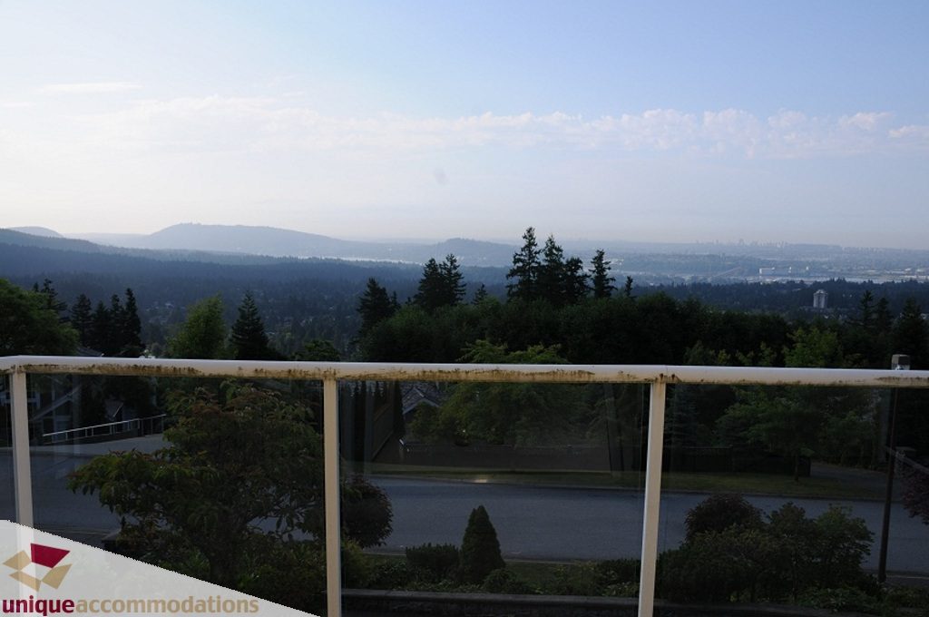 Furnished living room with city view and lush greenery. - 4139 Citadel Court, North Vancouver