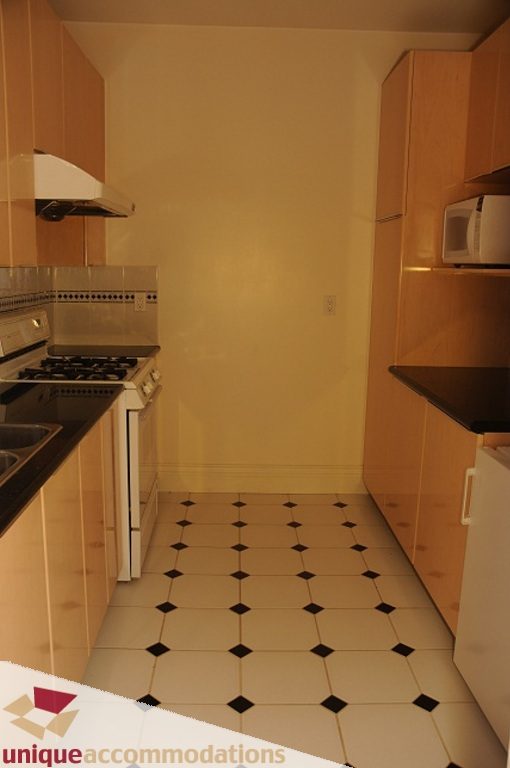 Bright kitchen with wooden cabinets, black and white tiled floor, and stainless steel appliances. - 4139 Citadel Court, North Vancouver