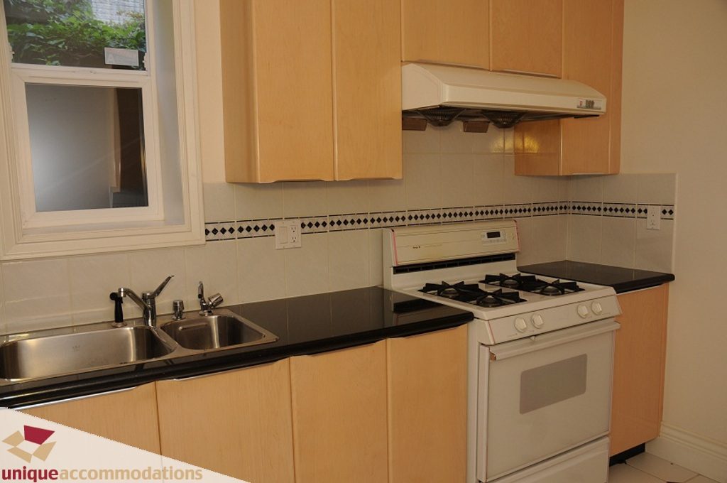 Bright kitchen with black countertops, white appliances, and wooden cabinets. - 4139 Citadel Court, North Vancouver