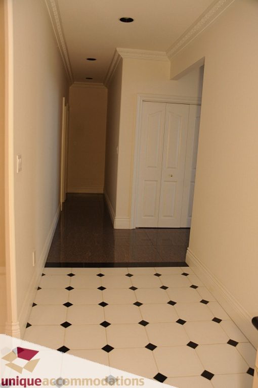 Bright hallway with black and white checkered tile floor, white walls, and a white door. - 4139 Citadel Court, North Vancouver