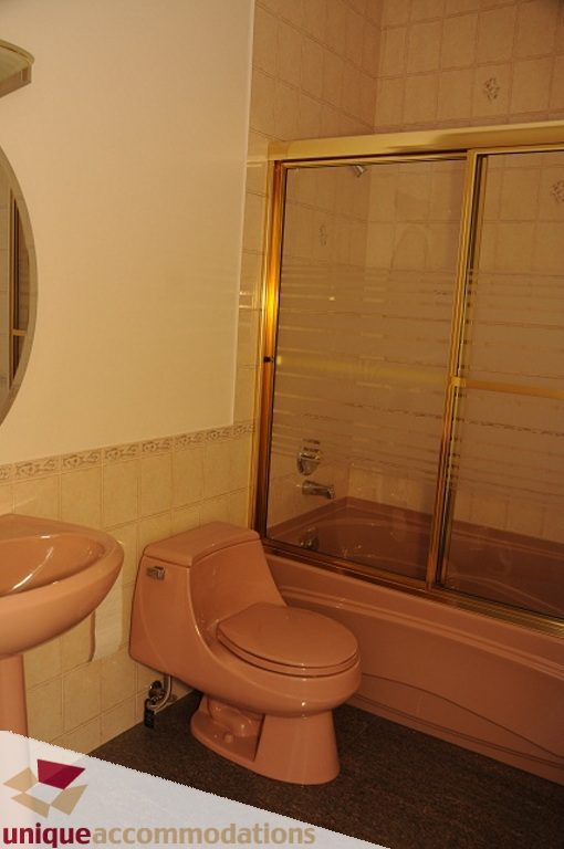 Bathroom with pink fixtures and glass shower door. - 4139 Citadel Court, North Vancouver