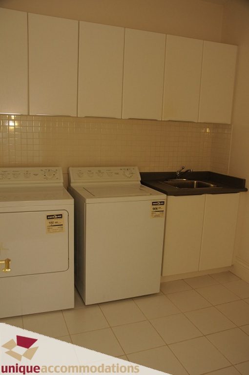 Bright laundry room with white cabinets and tiled countertops. - 4139 Citadel Court, North Vancouver
