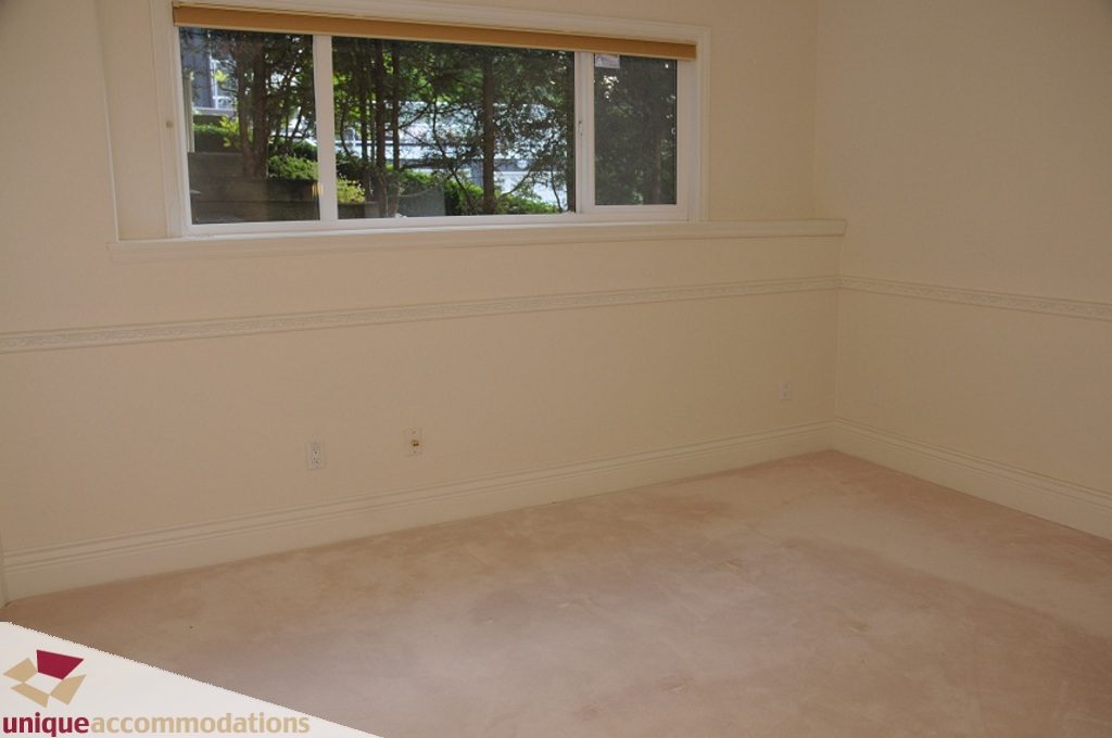 Empty bedroom with carpeted floor and large window showing trees. - 4139 Citadel Court, North Vancouver