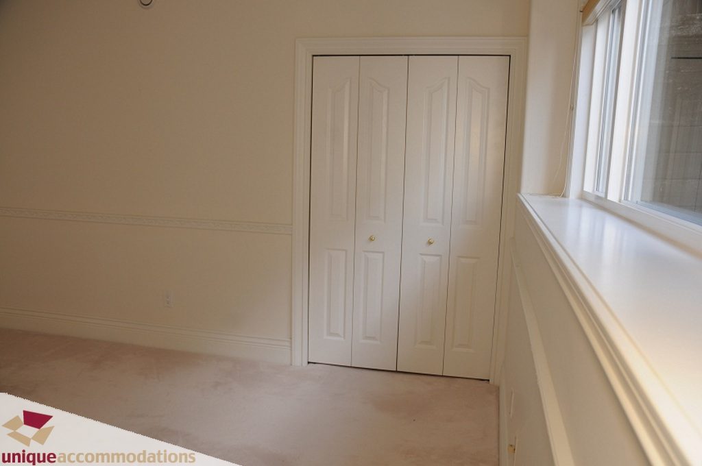 Bright bedroom with white closet doors and large windows, natural light. - 4139 Citadel Court, North Vancouver