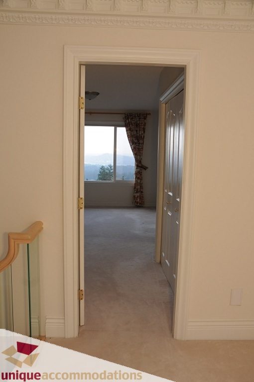 Bright hallway leading to a room with a city view and patterned curtains. - 4139 Citadel Court, North Vancouver