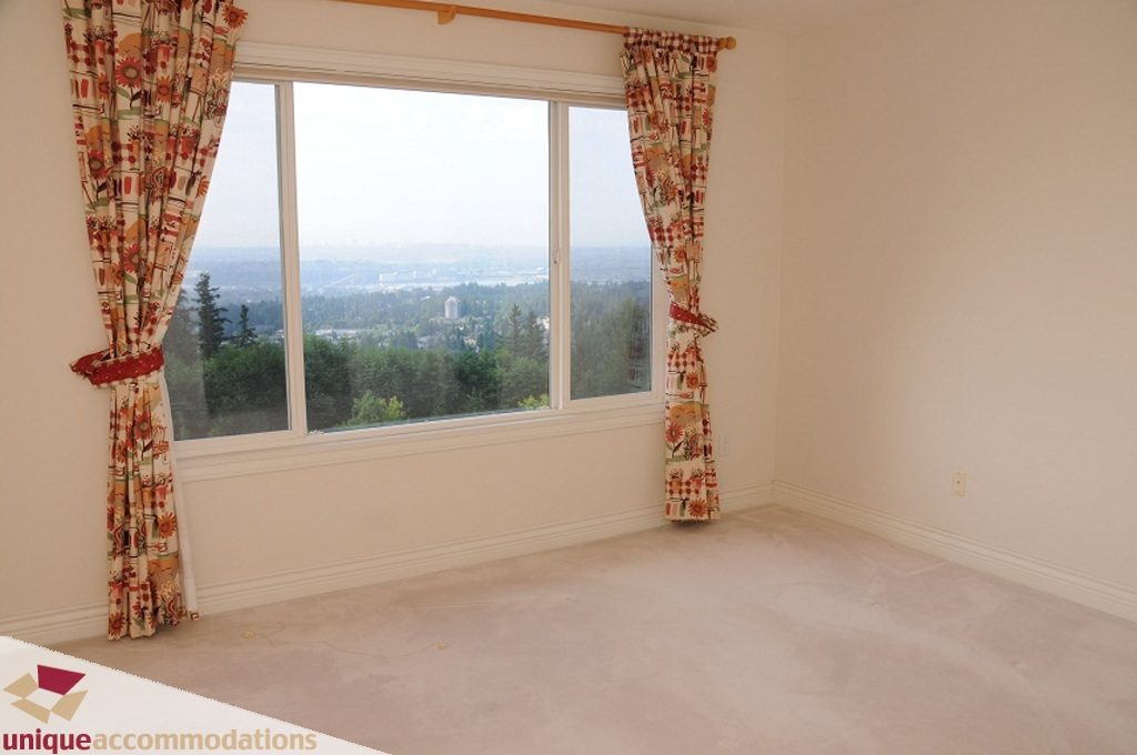 Bright living room with large windows offering a city view and floral curtains. - 4139 Citadel Court, North Vancouver