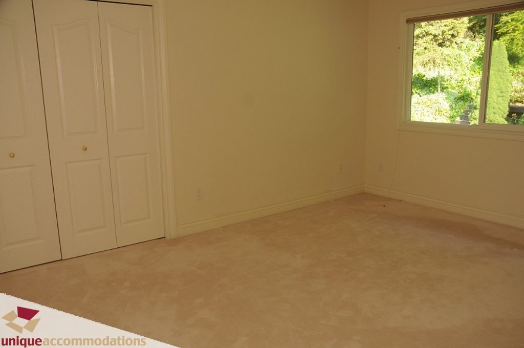Empty bedroom with carpeted floor and closet doors. - 4139 Citadel Court, North Vancouver