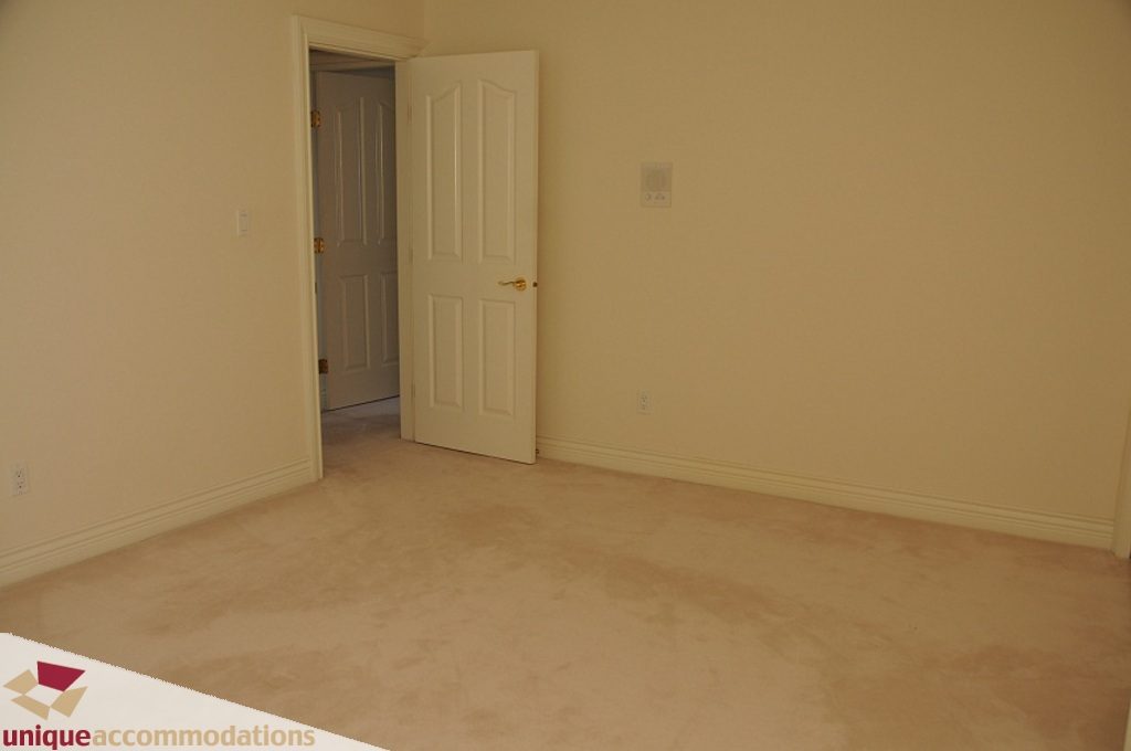 Empty bedroom with beige carpet and white walls. - 4139 Citadel Court, North Vancouver