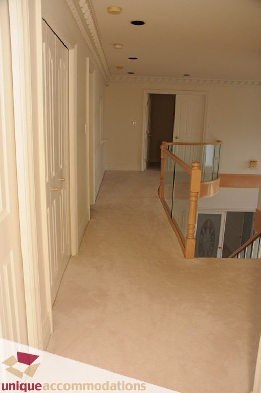 Staircase leading to upper level with wooden railings and carpeted floors. - 4139 Citadel Court, North Vancouver