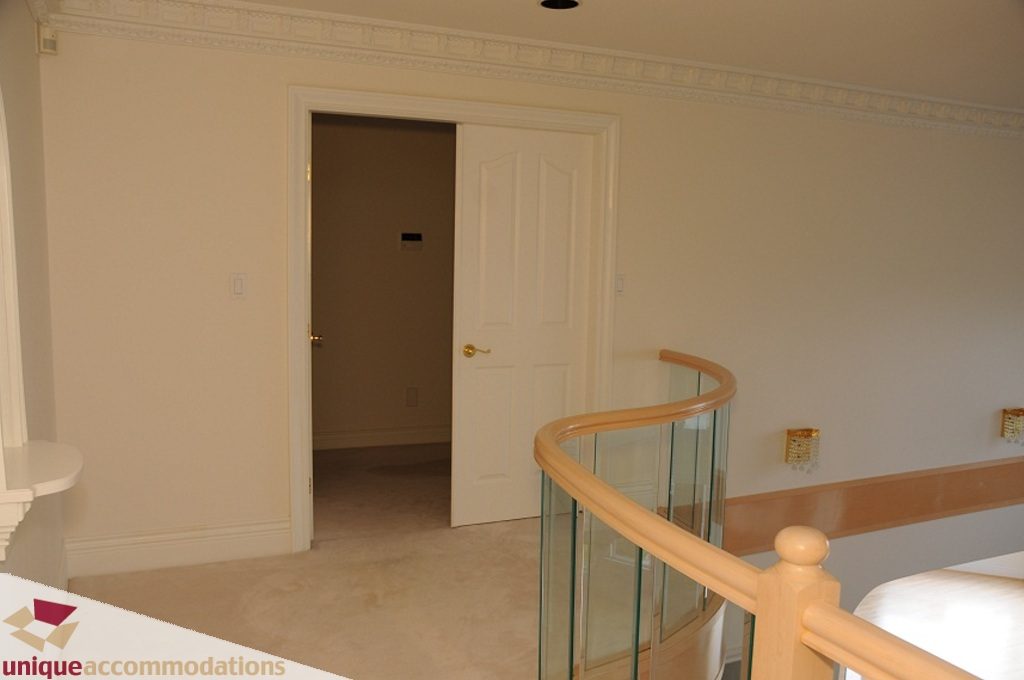 Staircase leading to upper level with glass railings and beige walls. - 4139 Citadel Court, North Vancouver