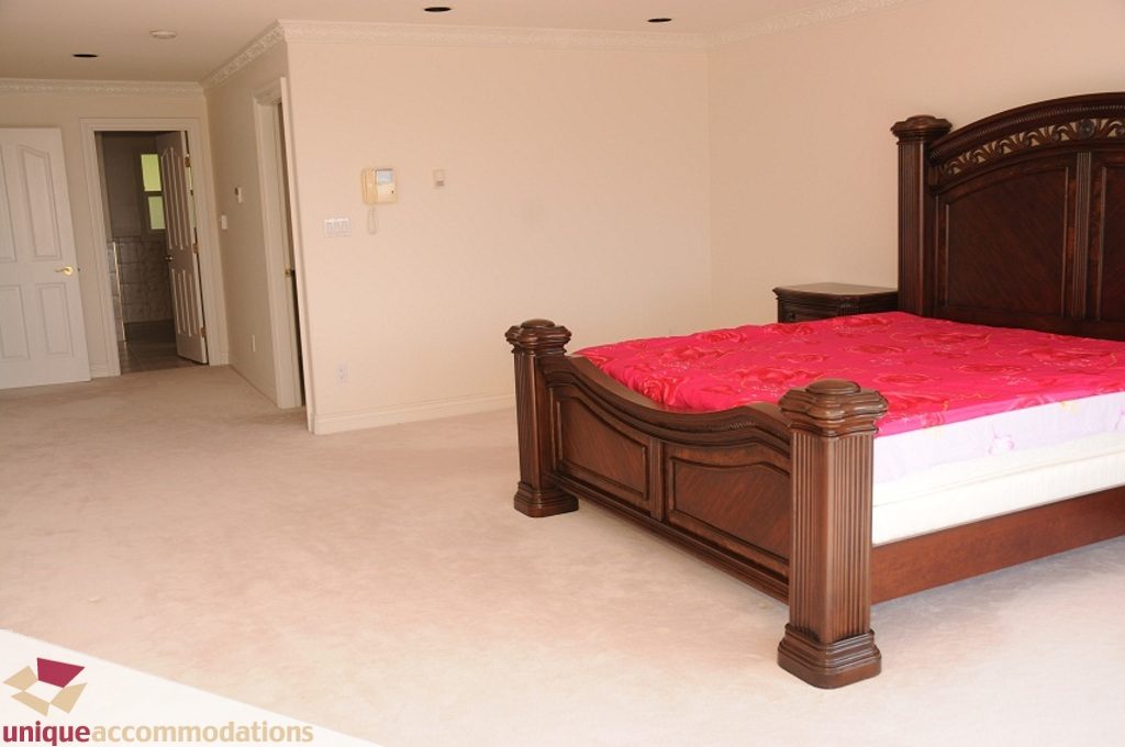 Spacious bedroom with two large beds, wooden headboards, and pink bedding. - 4139 Citadel Court, North Vancouver
