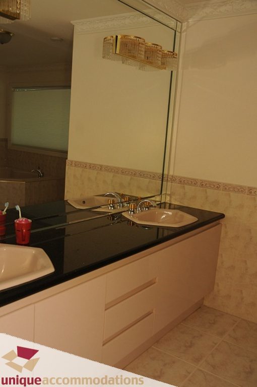 Modern bathroom with black countertops and large mirror. - 4139 Citadel Court, North Vancouver