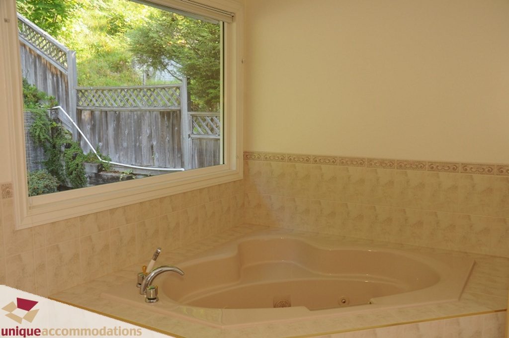 Bright bathroom with large window, tiled walls, and a soaking tub. - 4139 Citadel Court, North Vancouver