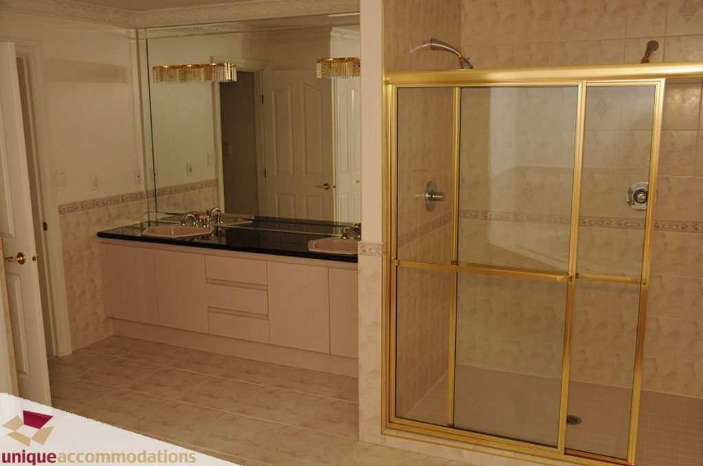 Bathroom with large mirror, black countertops, and gold-framed shower. - 4139 Citadel Court, North Vancouver