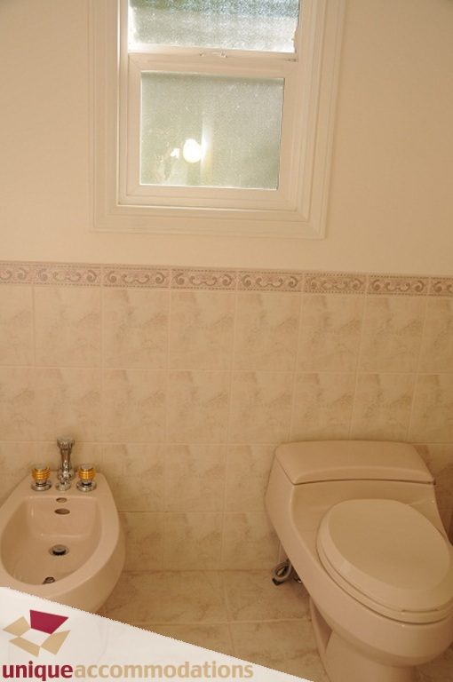 Bathroom with beige tiles and a window above the toilet. - 4139 Citadel Court, North Vancouver