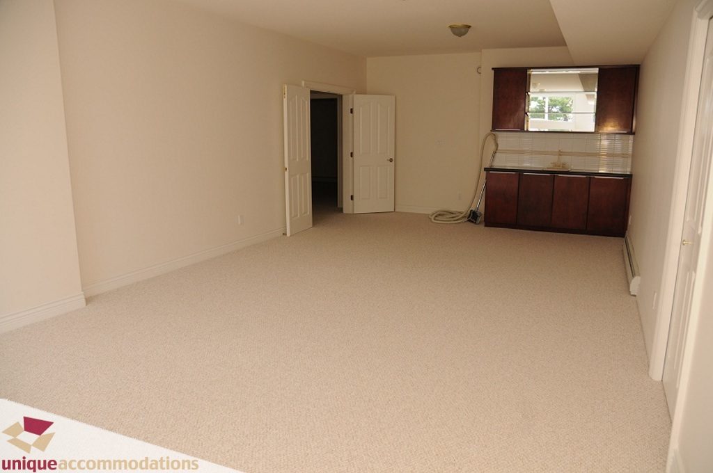Bright living room with beige carpet and dark wood cabinets. - 4139 Citadel Court, North Vancouver