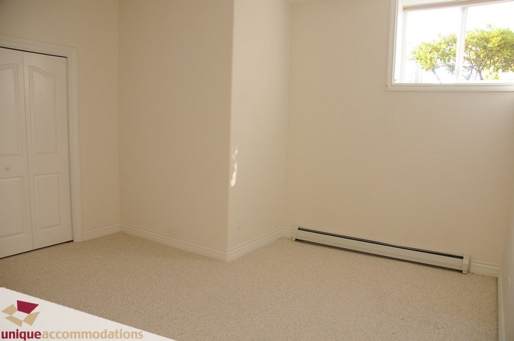 Bright bedroom with beige carpet and white walls, natural light from window. - 4139 Citadel Court, North Vancouver
