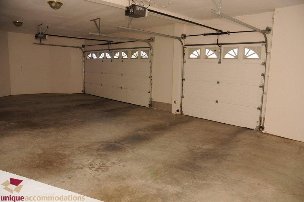 Large, empty garage with concrete floor and double doors. - 4139 Citadel Court, North Vancouver