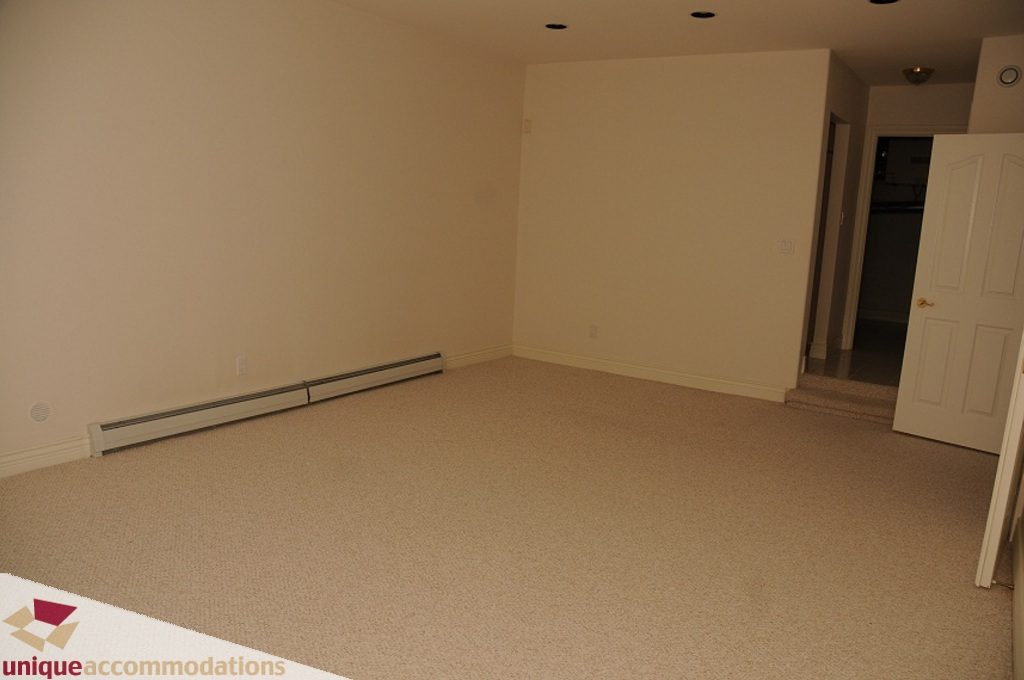 Empty living room with beige carpet and white walls. - 4139 Citadel Court, North Vancouver