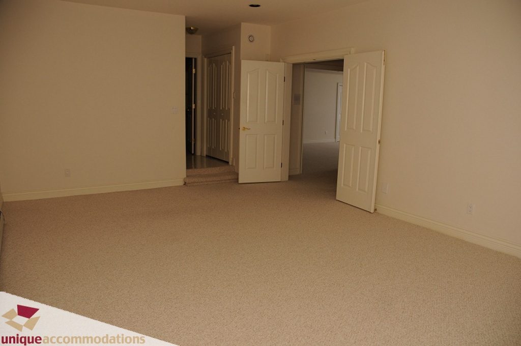 Spacious living room with carpeted floors and multiple doorways leading to other rooms. - 4139 Citadel Court, North Vancouver