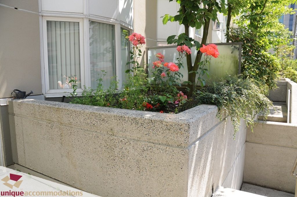 Bright balcony with concrete planters, vibrant flowers, and a view of the city. - 4139 Citadel Court, North Vancouver