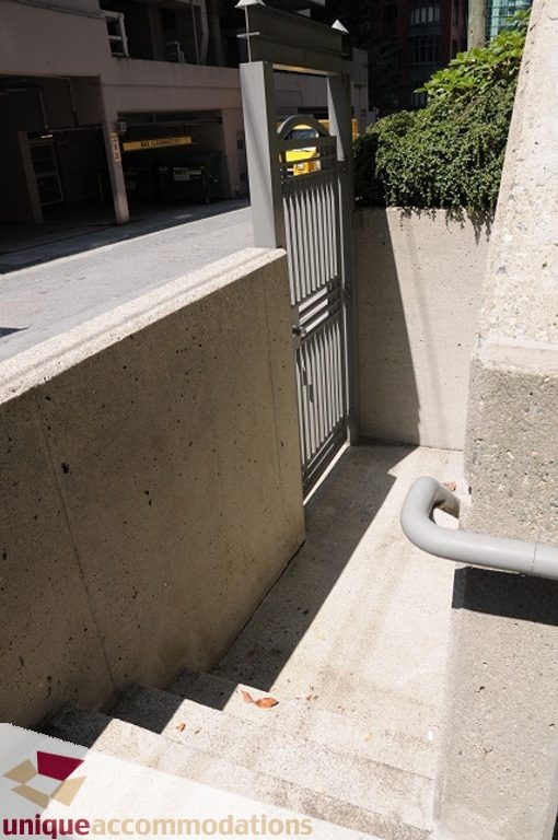 Concrete staircase leading to a gated entrance, with a railing and shadows on the steps. - 4139 Citadel Court, North Vancouver