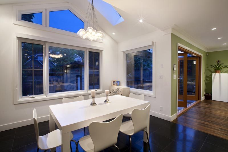 Furnished dining room with white table, modern chairs, hardwood floors, and large windows. - 4104 West 12th Avenue, Vancouver West Side