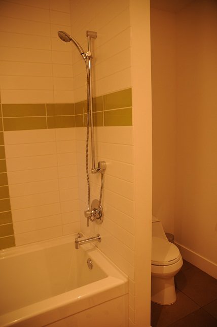 Bathroom with white bathtub, green accent tiles, and modern fixtures. - 4104 West 12th Avenue, Vancouver West Side