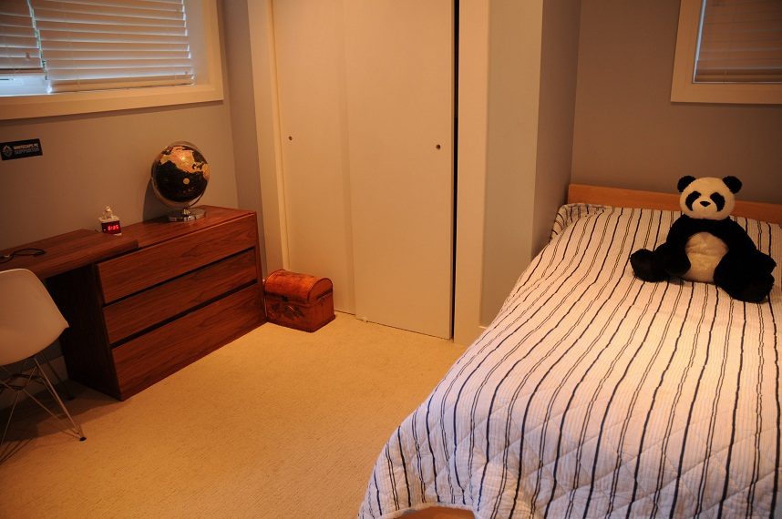 Bedroom with striped bedding and panda plush, wooden dresser, and globe. - 4104 West 12th Avenue, Vancouver West Side