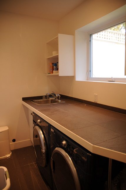 Bright kitchen with dark countertops and a window, perfect for a cozy living space. - 4104 West 12th Avenue, Vancouver West Side