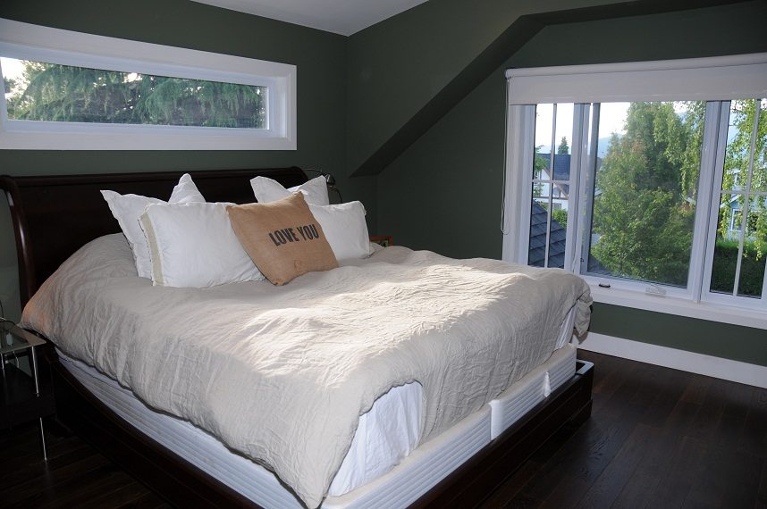 Spacious bedroom with dark wood floors, large windows, and a cozy bed setup. - 4104 West 12th Avenue, Vancouver West Side