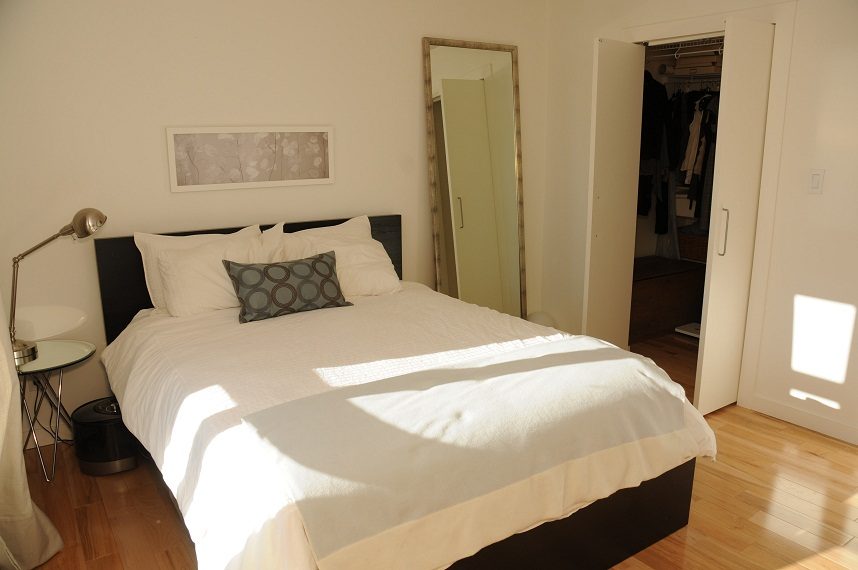 Bright bedroom with hardwood floors and a neatly made bed with white linens and a patterned pillow. - 411- 2161 West 12th Avenue, Vancouver West Side