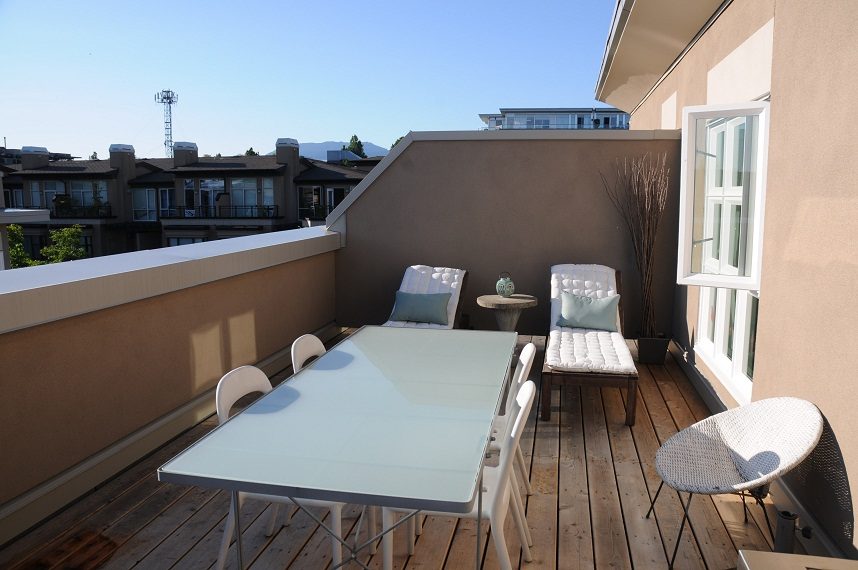 Furnished rooftop patio with wooden deck, white furniture, and city views. - 411- 2161 West 12th Avenue, Vancouver West Side