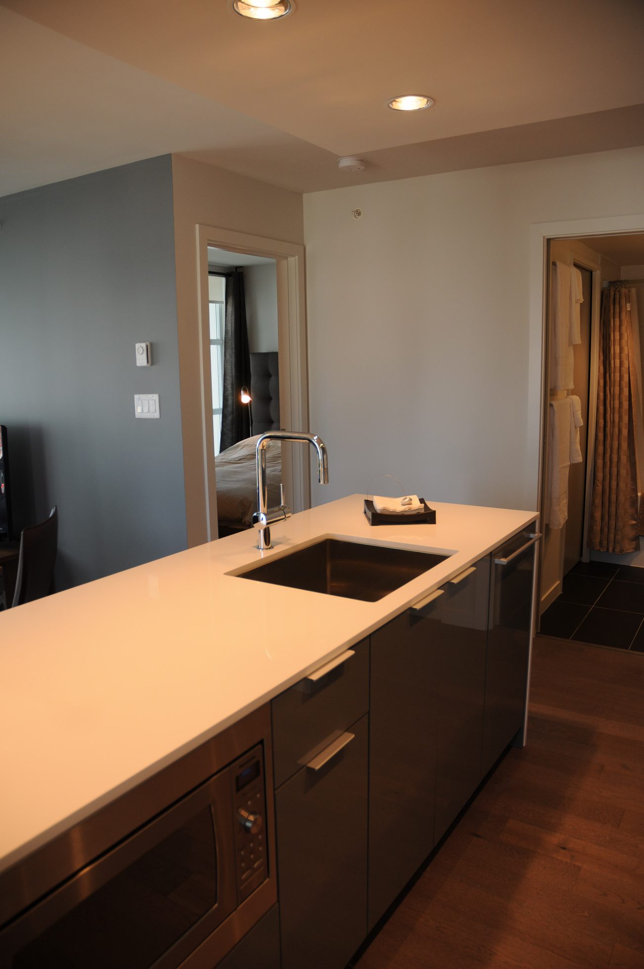 Bright kitchen with white countertops and modern sink, hardwood floors, and a view of the bedroom. - 801 - 161 West Georgia, Vancouver Downtown