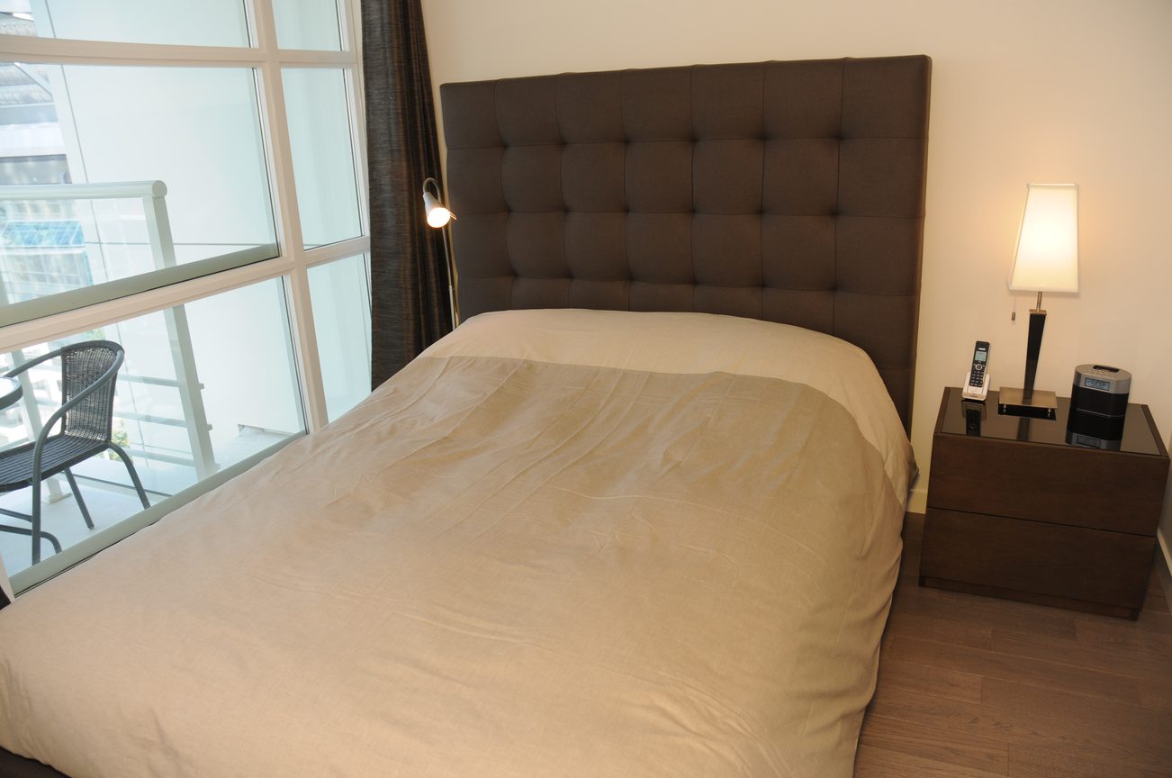 Furnished bedroom with tufted headboard, hardwood floors, and city view. - 801 - 161 West Georgia, Vancouver Downtown