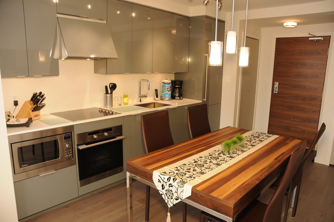 Bright kitchen with modern appliances, wooden dining table, and hardwood floors. - 2009 - 161 West Georgia, Vancouver Downtown