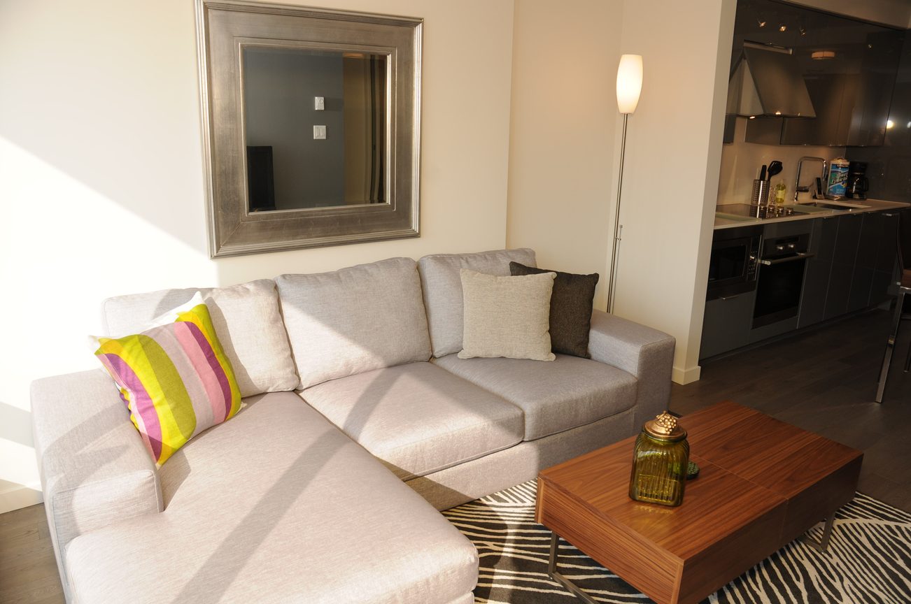 Bright living room with modern furniture, zebra print rug, and kitchen in the background. - 2009 - 161 West Georgia, Vancouver Downtown