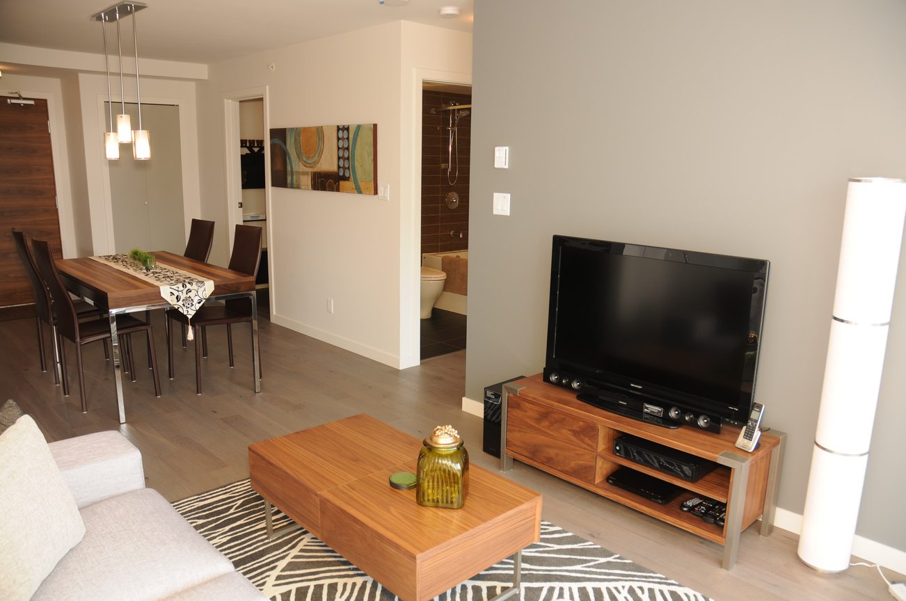 Furnished living room with hardwood floors, modern furniture, and a large TV. - 2009 - 161 West Georgia, Vancouver Downtown