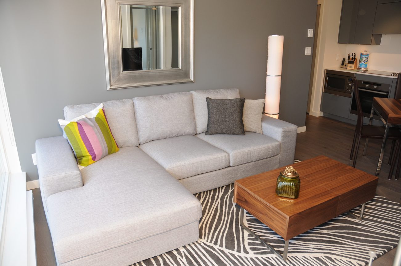 Furnished living room with modern sectional sofa, zebra print rug, and hardwood floors. - 2201 - 161 West Georgia, Vancouver Downtown