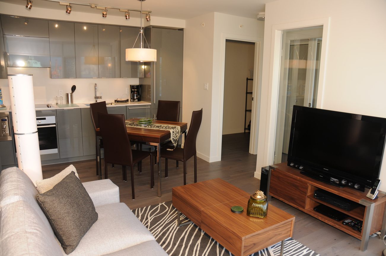 Bright kitchen with modern appliances and a dining area featuring a wooden table and dark chairs. - 2201 - 161 West Georgia, Vancouver Downtown